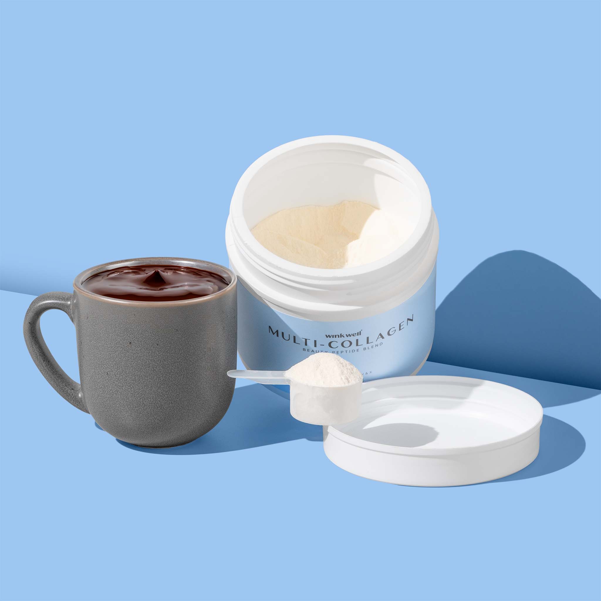An open tub of Wink Well Unflavored Multi-Collagen next to a full mug of coffee