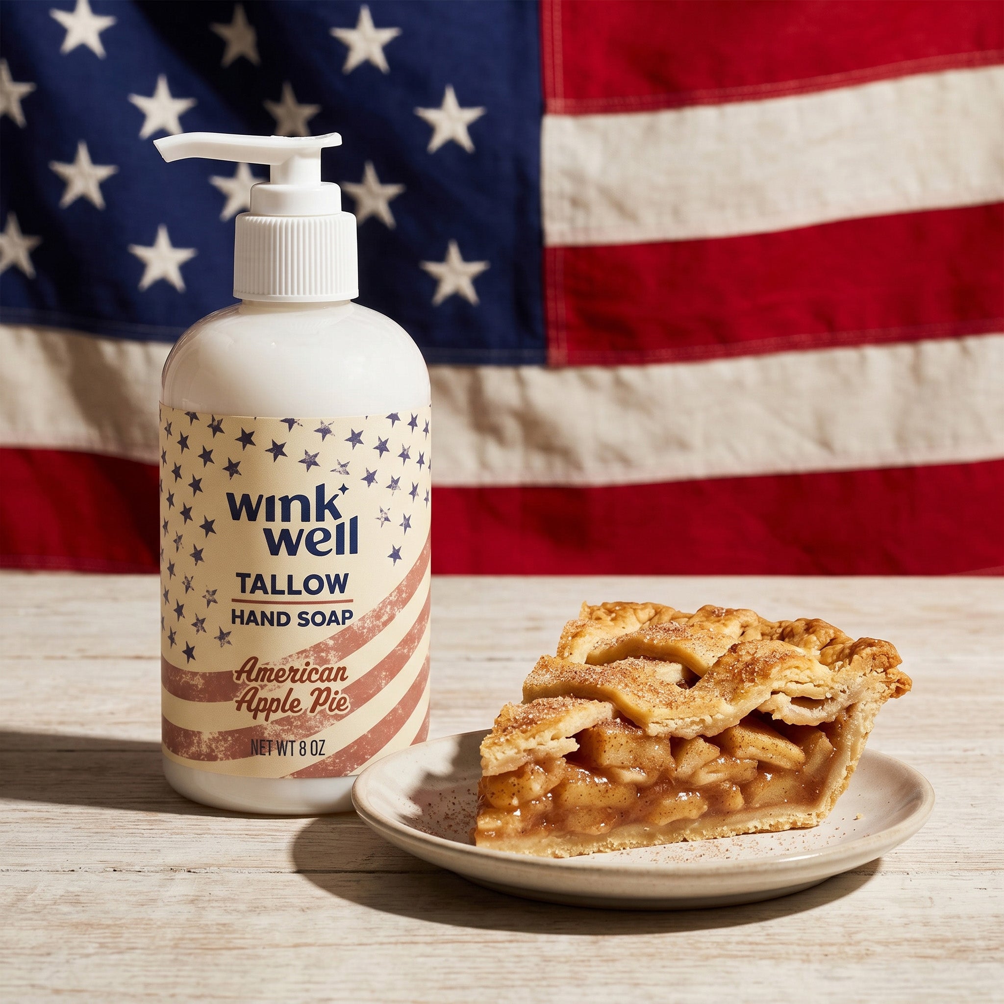 Wink Well Tallow Hand Soap bottle in Apple Pie scent with a slice of apple pie on a wooden surface in front of an American flag.