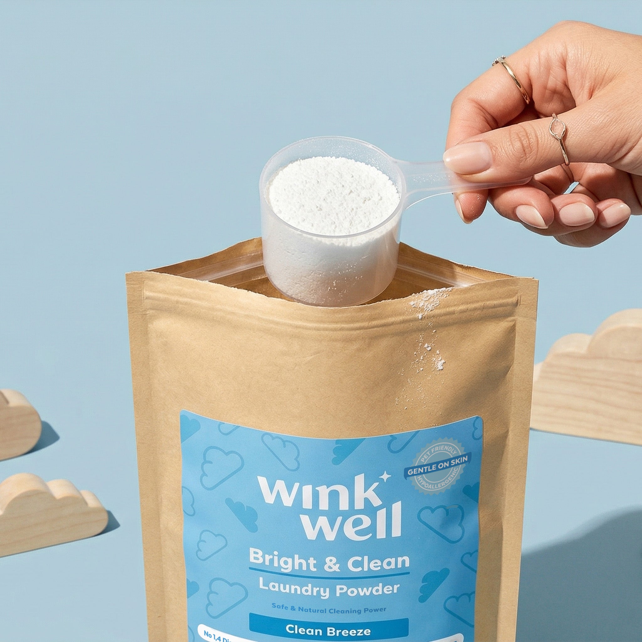 Wink Well laundry powder being poured from a container onto a package with a blue background
