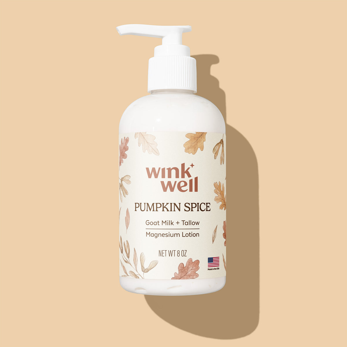 A white pump bottle of wink well Pumpkin Spice Goat Milk + Tallow Magnesium Lotion, decorated with autumn leaf illustrations, set against a solid beige background with a soft shadow.