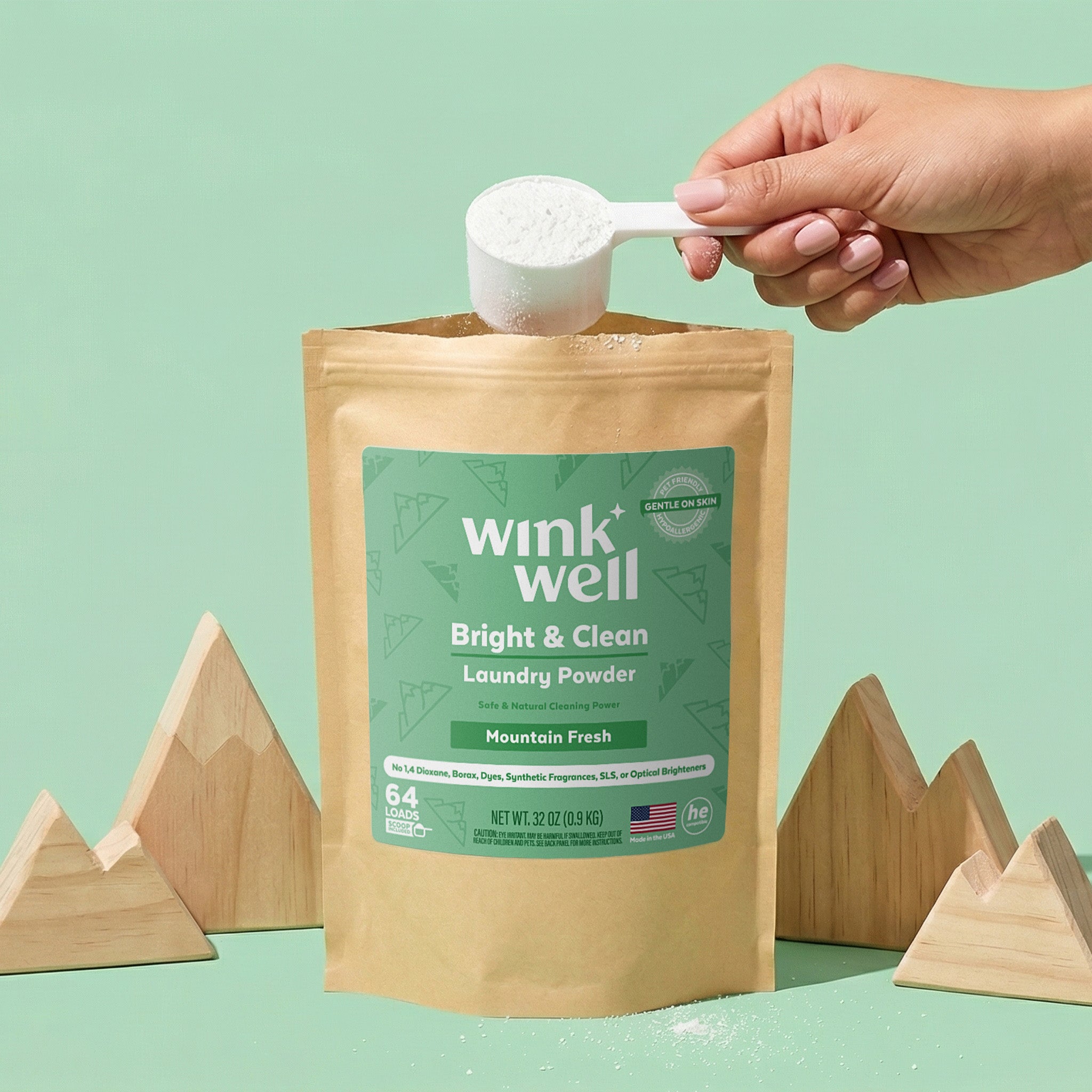 Wink Well laundry powder package with a hand holding a scoop against a green background